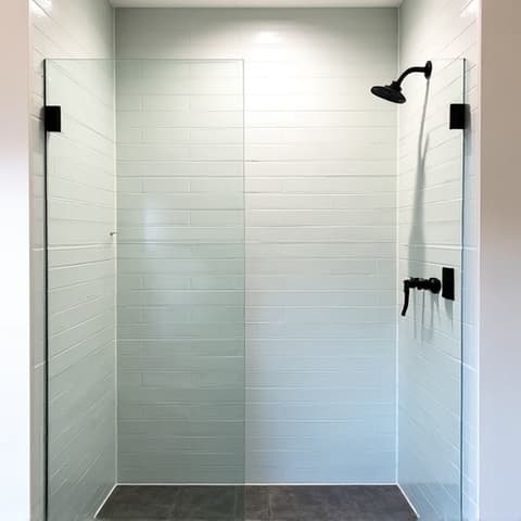 Before and after of a master bathroom tub-to-shower conversion in a San Antonio home with a low-threshold entry and custom tile work. This image showcases a modern bathroom transformation in San Antonio, highlighting accessibility and contemporary design.